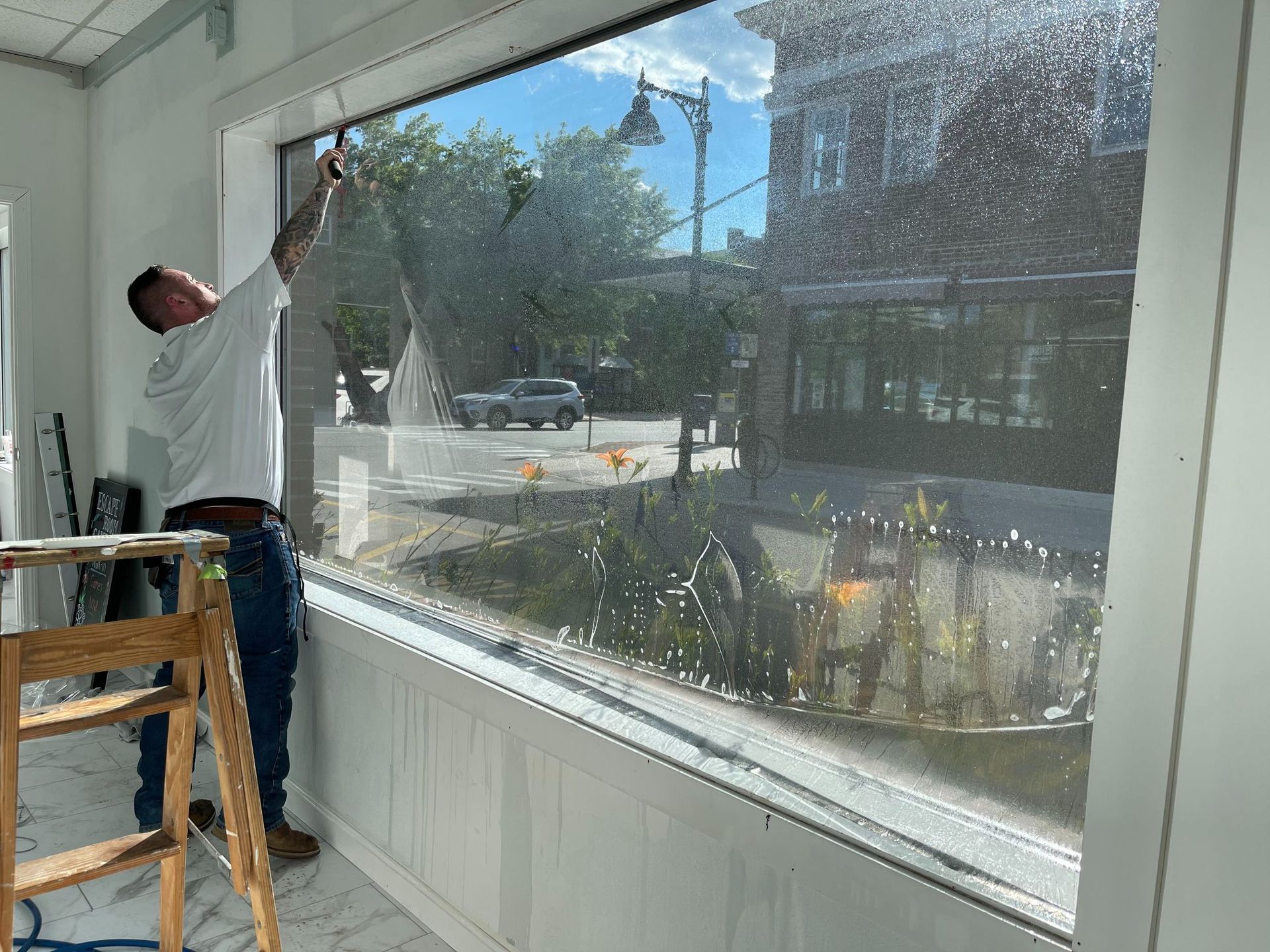 Man applying window film to a storefront window using a squeegee.