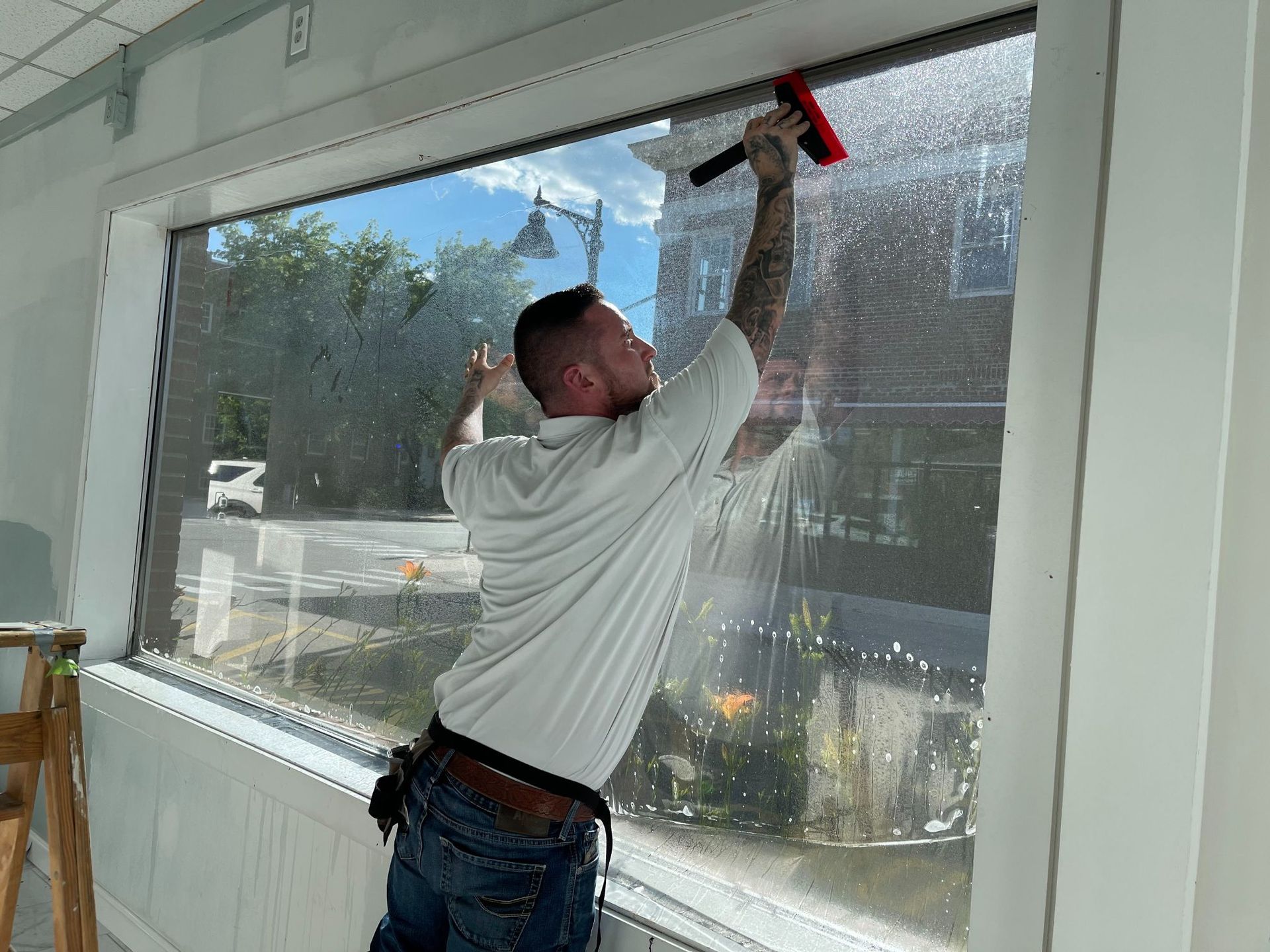 Person applying window film with a squeegee on a large window.