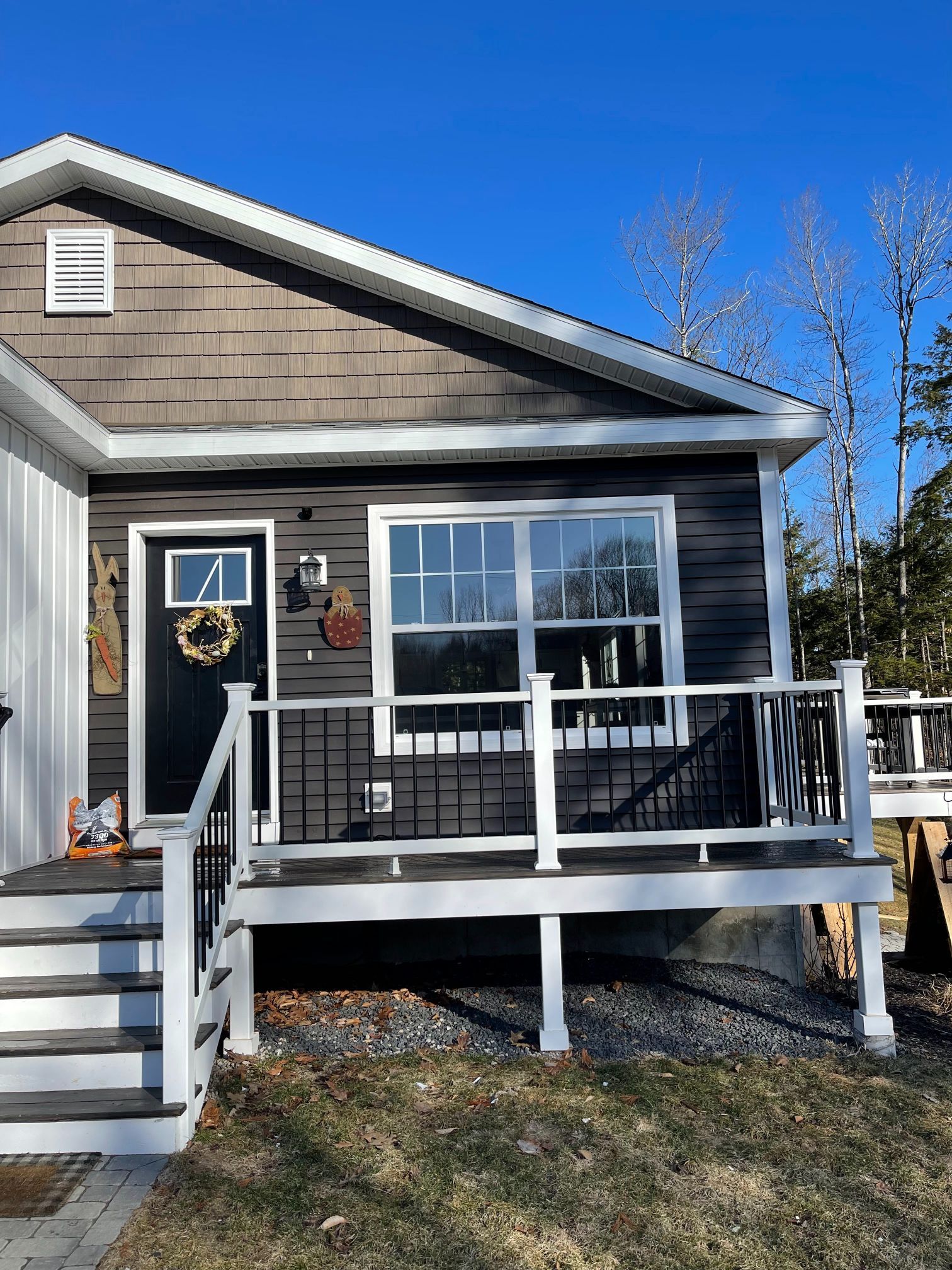 Small house with black door, gray siding, white trim, and a small porch.