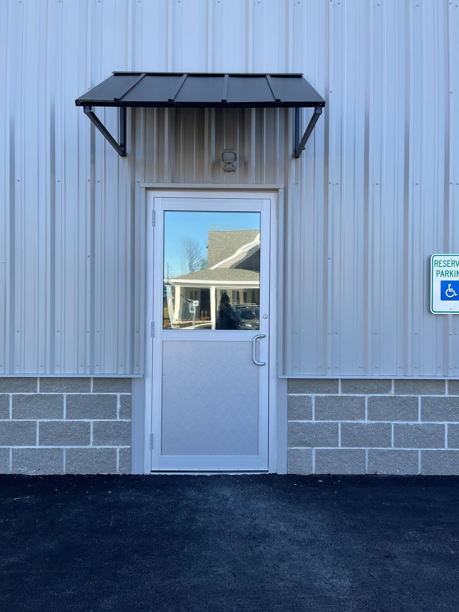 A metal door with an awning on a building with a handicap parking sign.