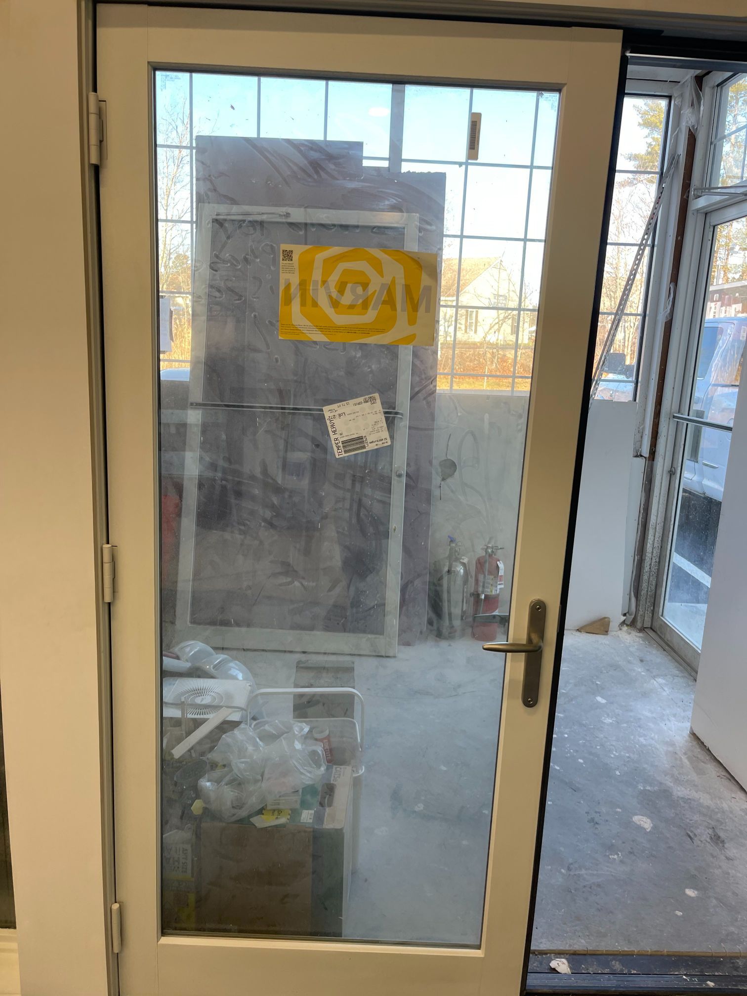 White framed glass door with a silver handle. Behind it are building materials.