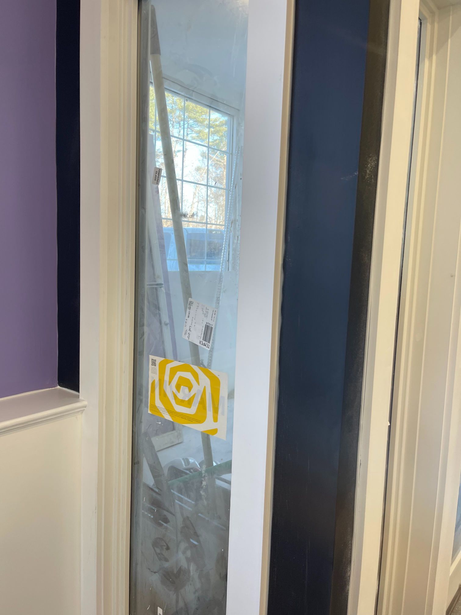 Glass door with white trim, stickers on glass, black wall adjacent.