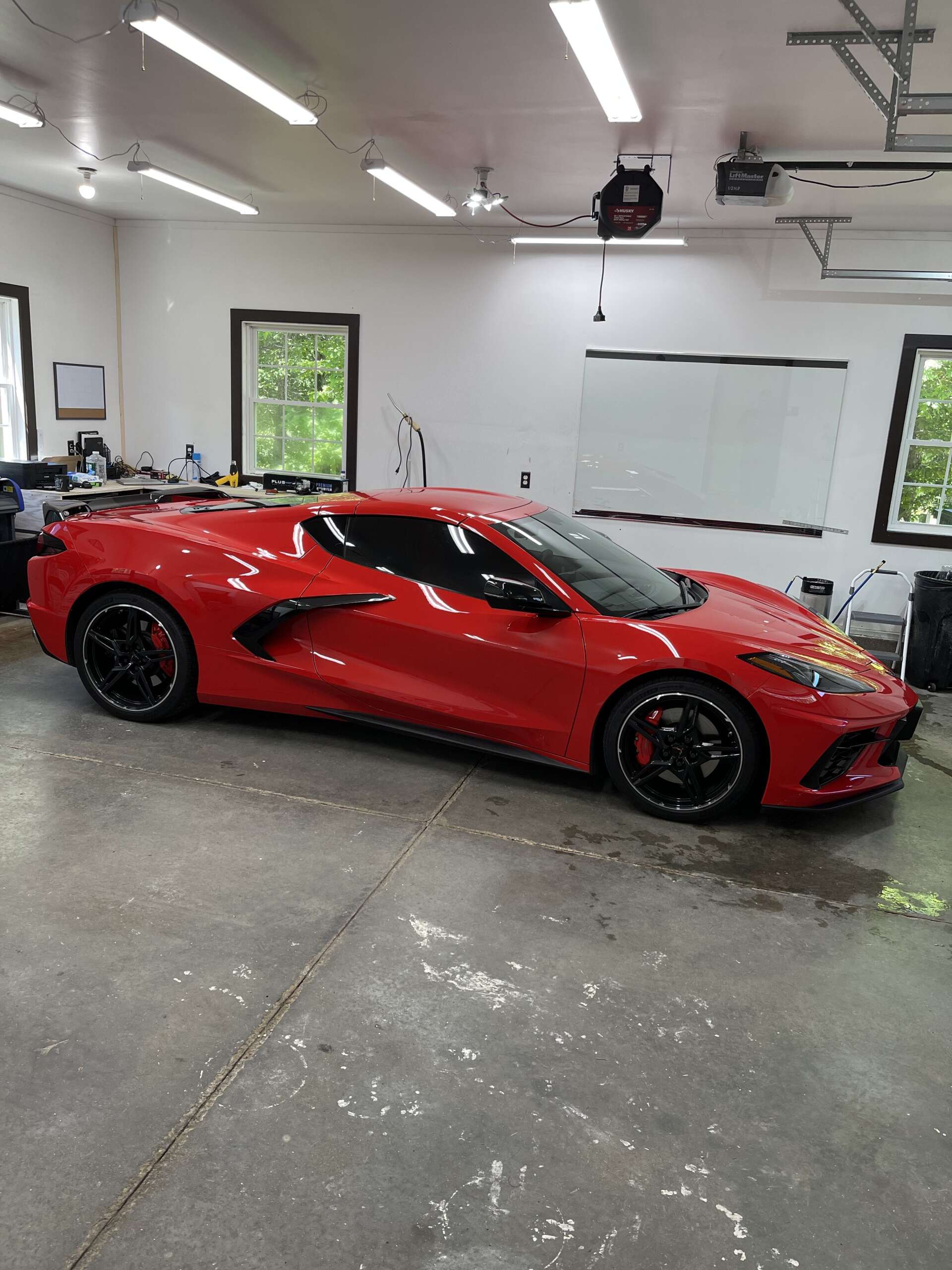 Red sports car in a garage with black wheels and tinted windows.