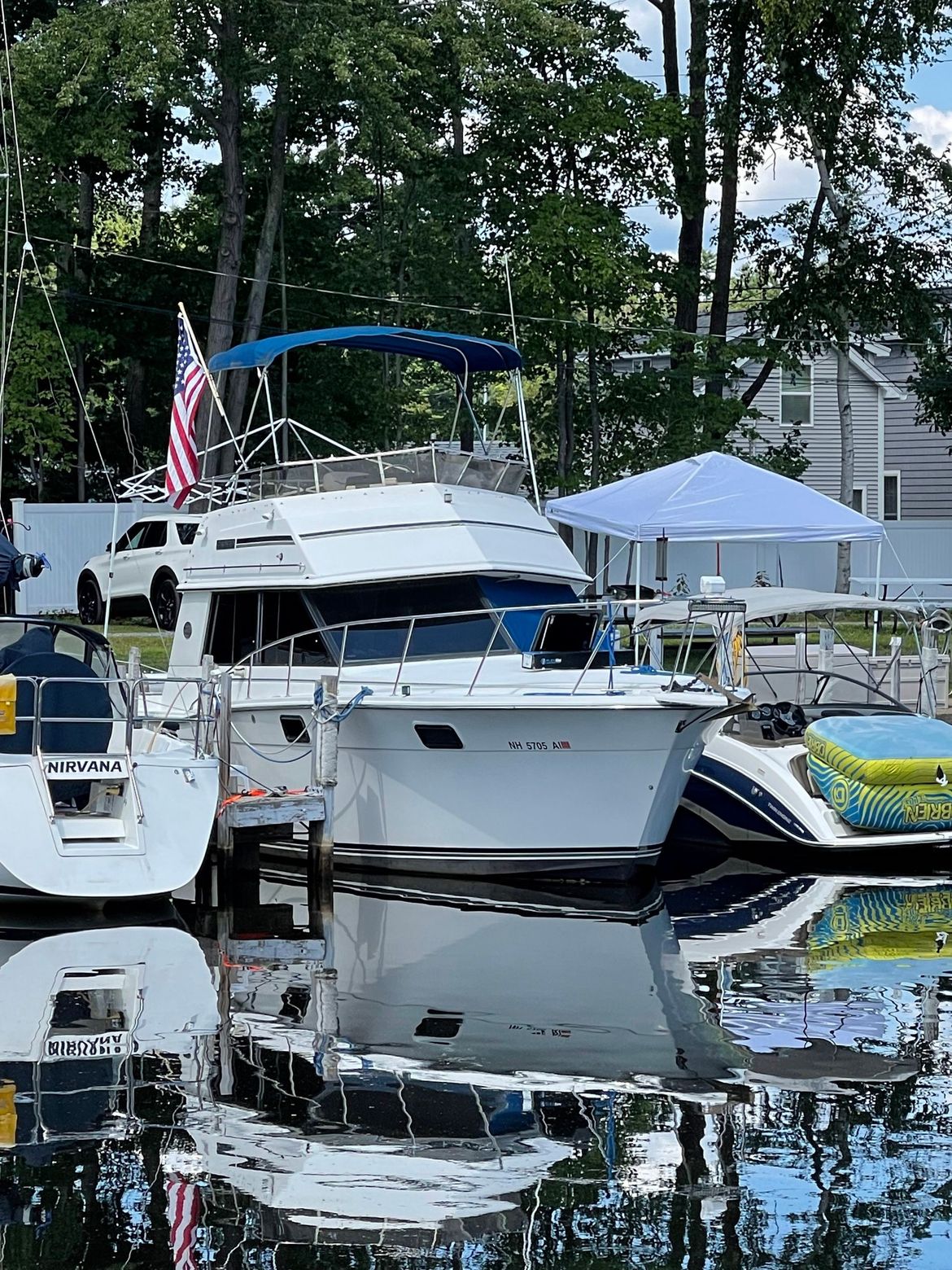 A white motorboat with blue accents docked at a marina, American flag waving.