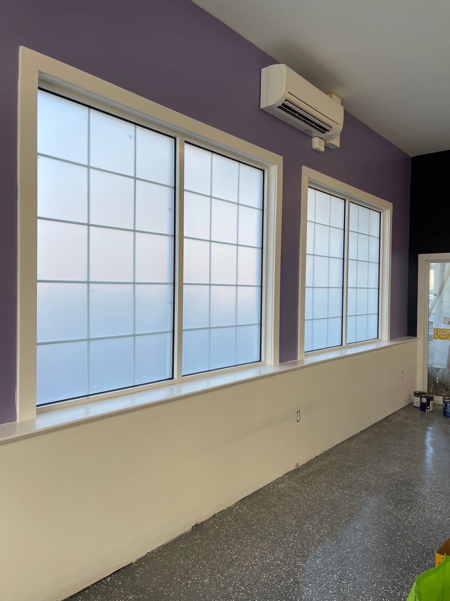 Purple wall with white trim windows, frosted glass, and a white lower wall in a room.