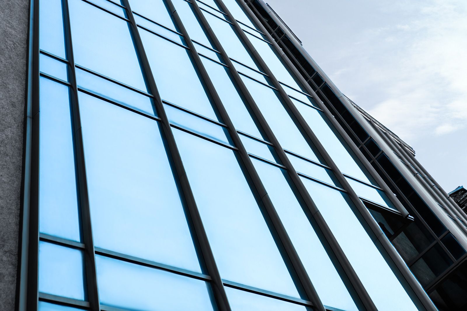 Modern skyscraper with blue-tinted windows reflects the sky.