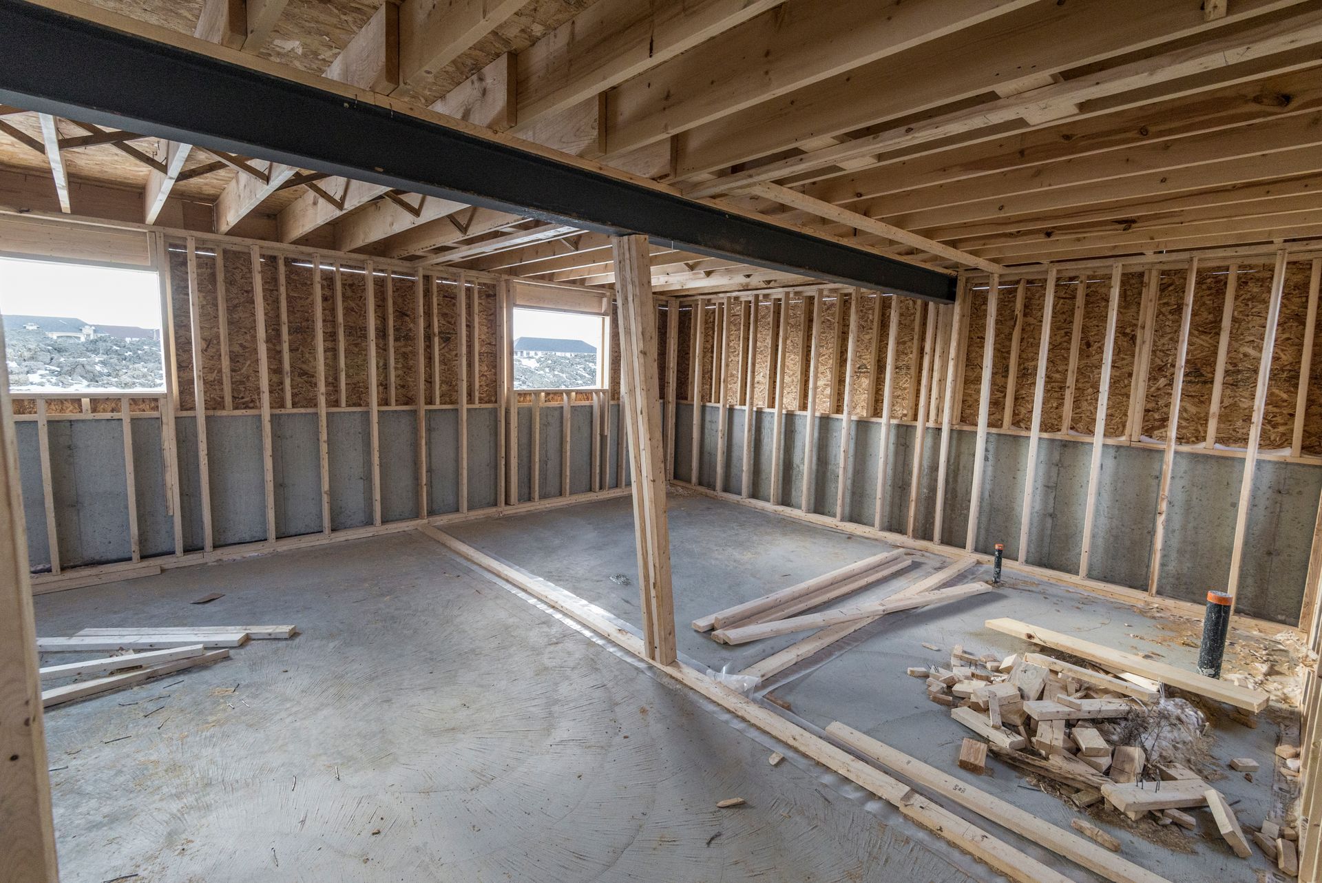 Dark unfinished basement with exposed joists, bare concrete walls, and stored boxes