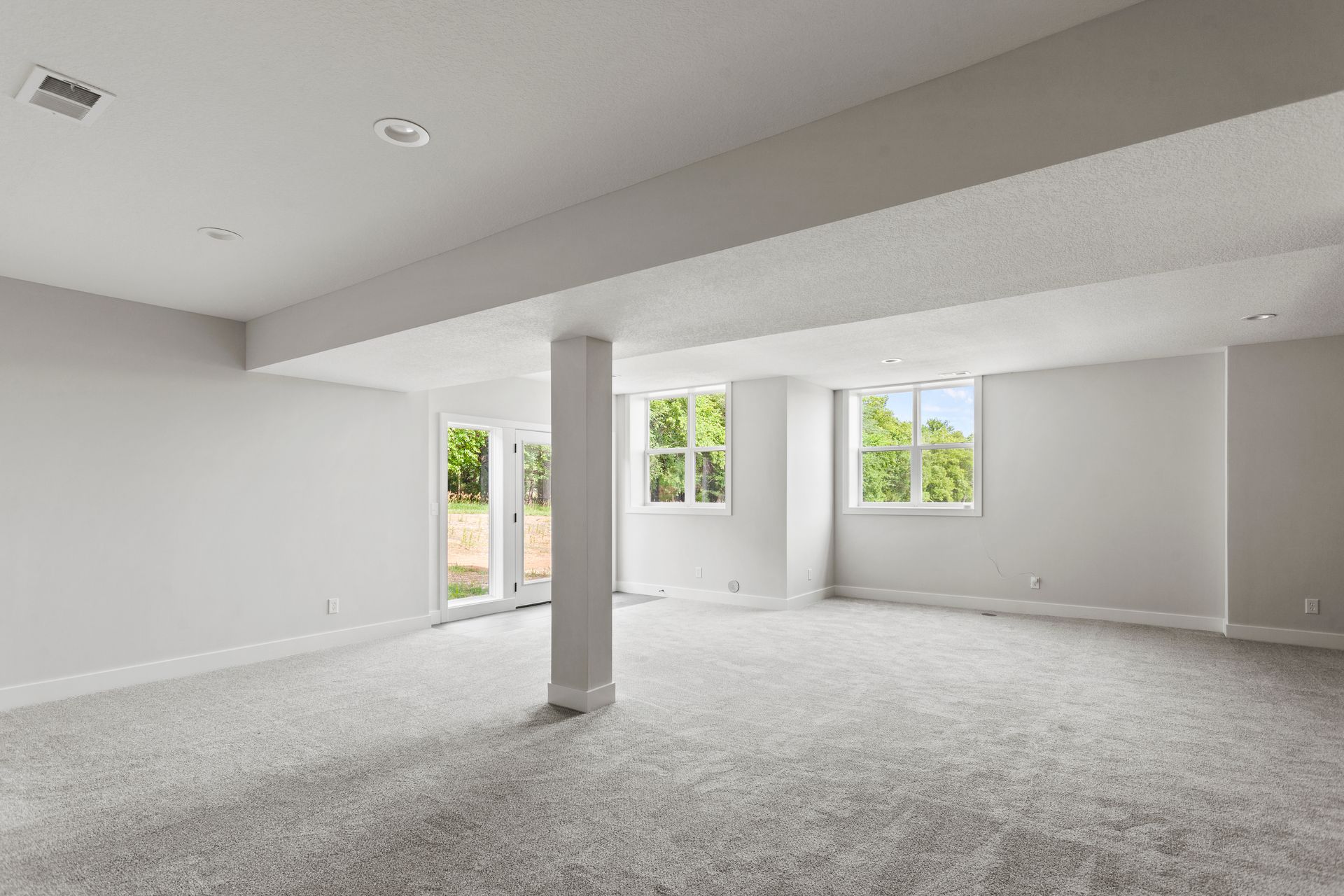 Contractor installing drywall in a partially finished Iowa basement with framing lumber and natural light