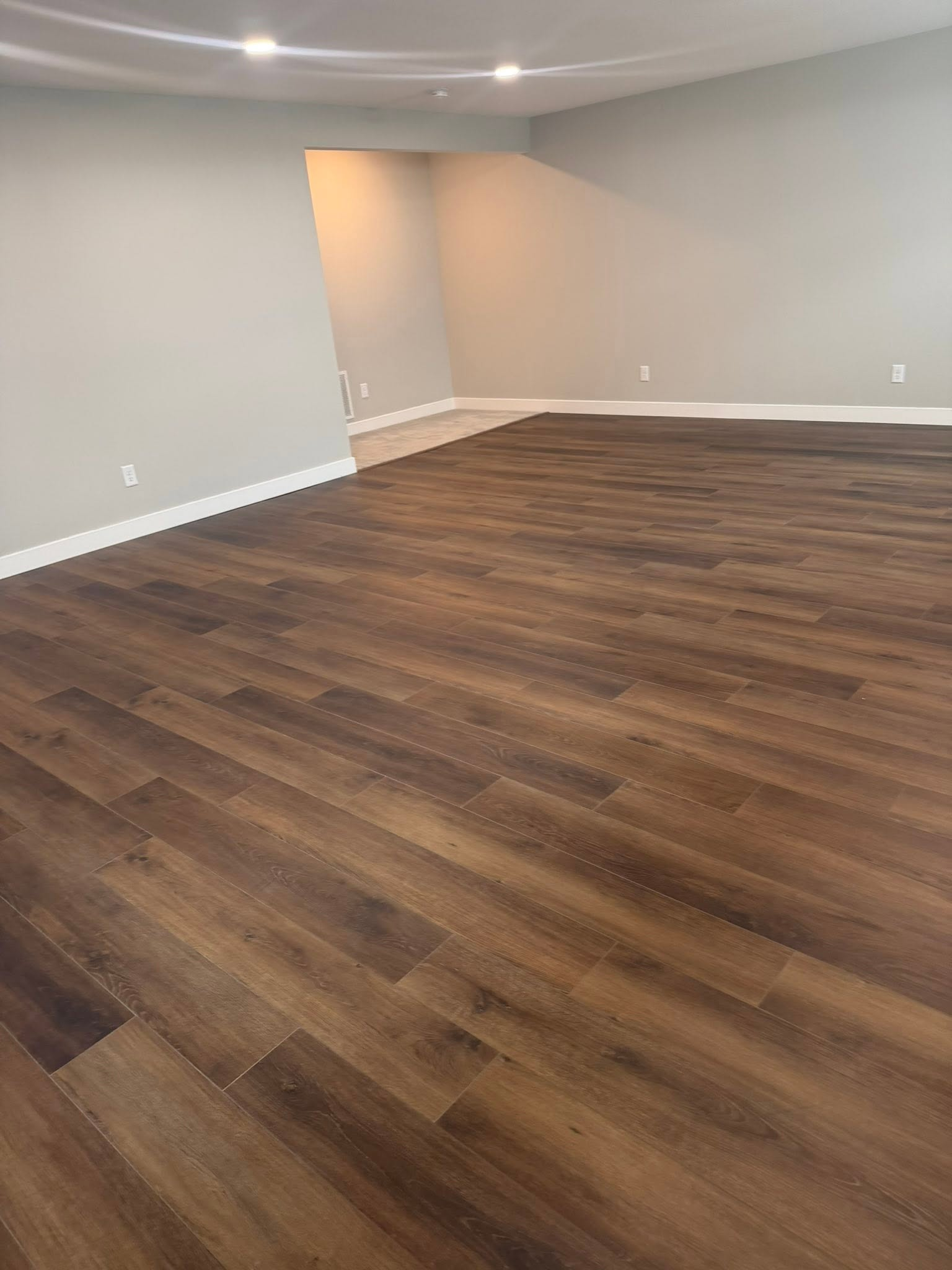 Damaged residential flooring with peeling vinyl edges near a kitchen threshold