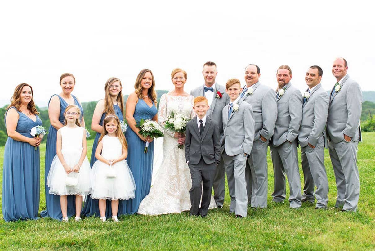 The bride and groom are posing for a picture with their wedding party.