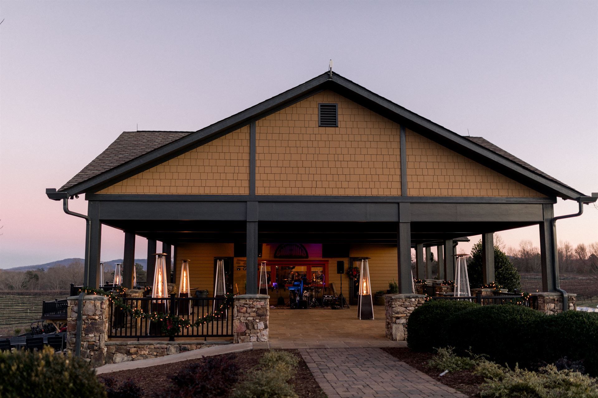 Covered outdoor venue with tan siding, dark trim, and a path leading to it.