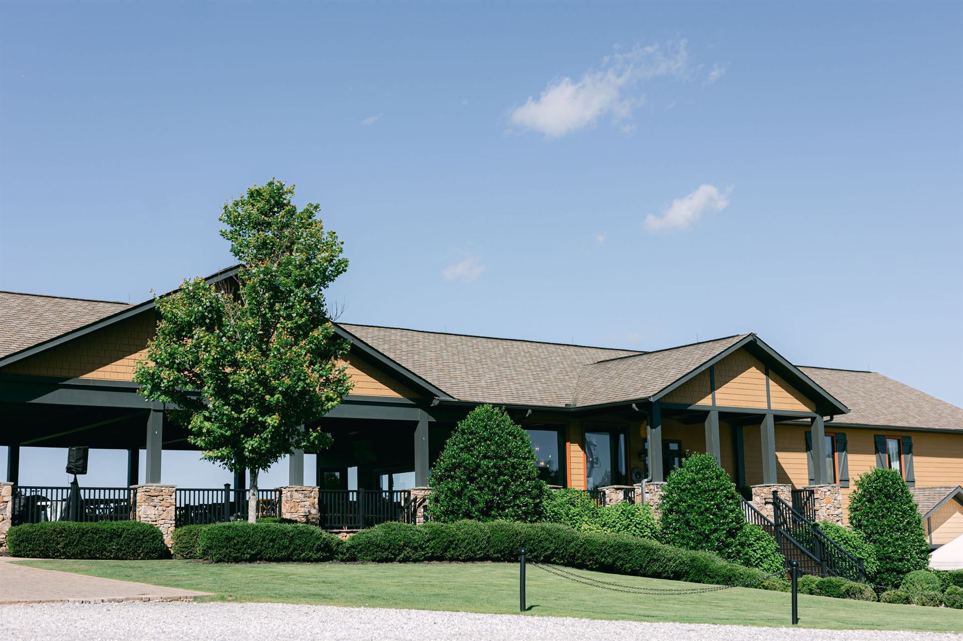 A long, yellow building with a dark roof and a porch, blue sky.