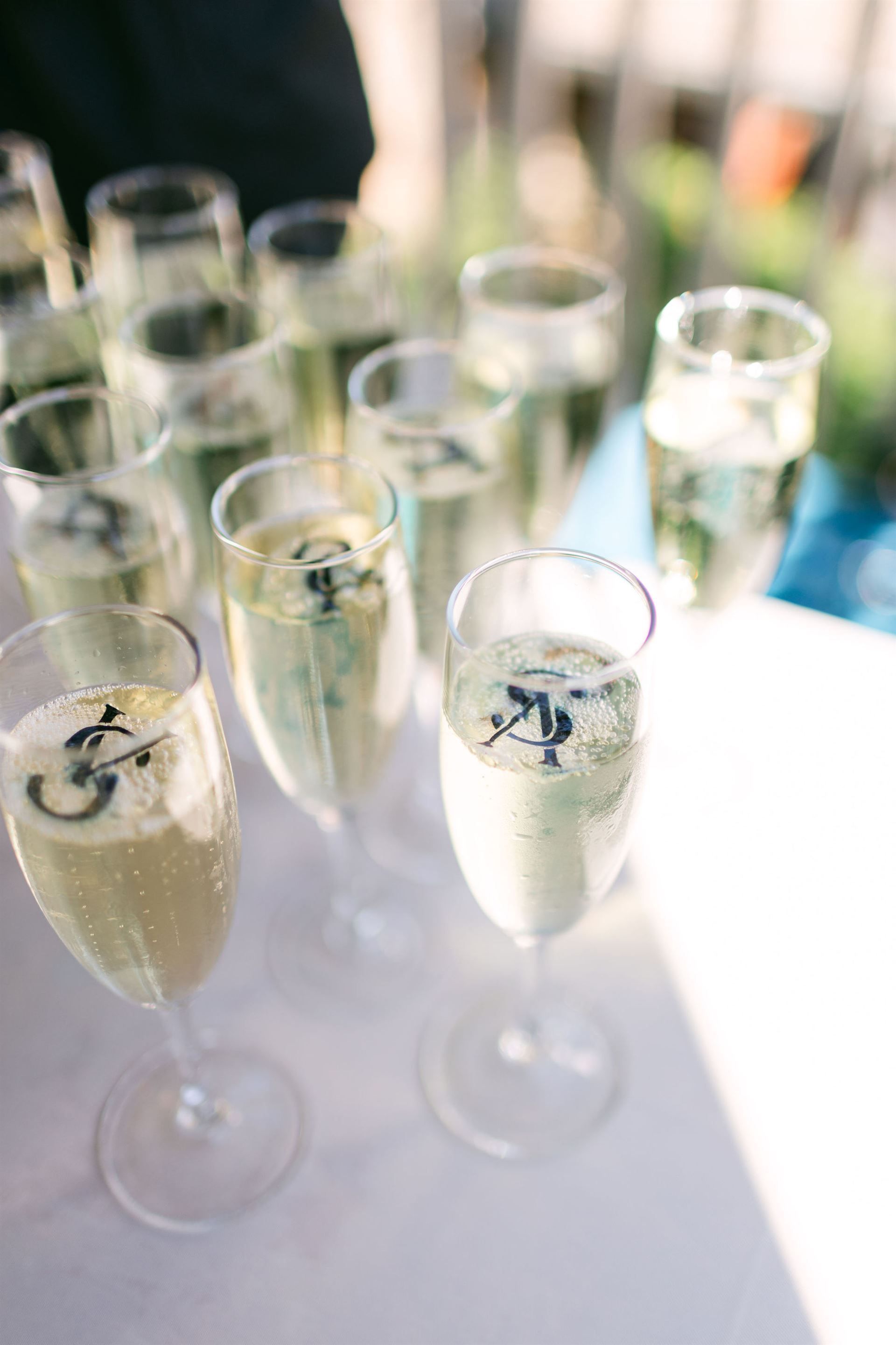 Champagne flutes with a black monogram, set on a white surface, bubbles visible.