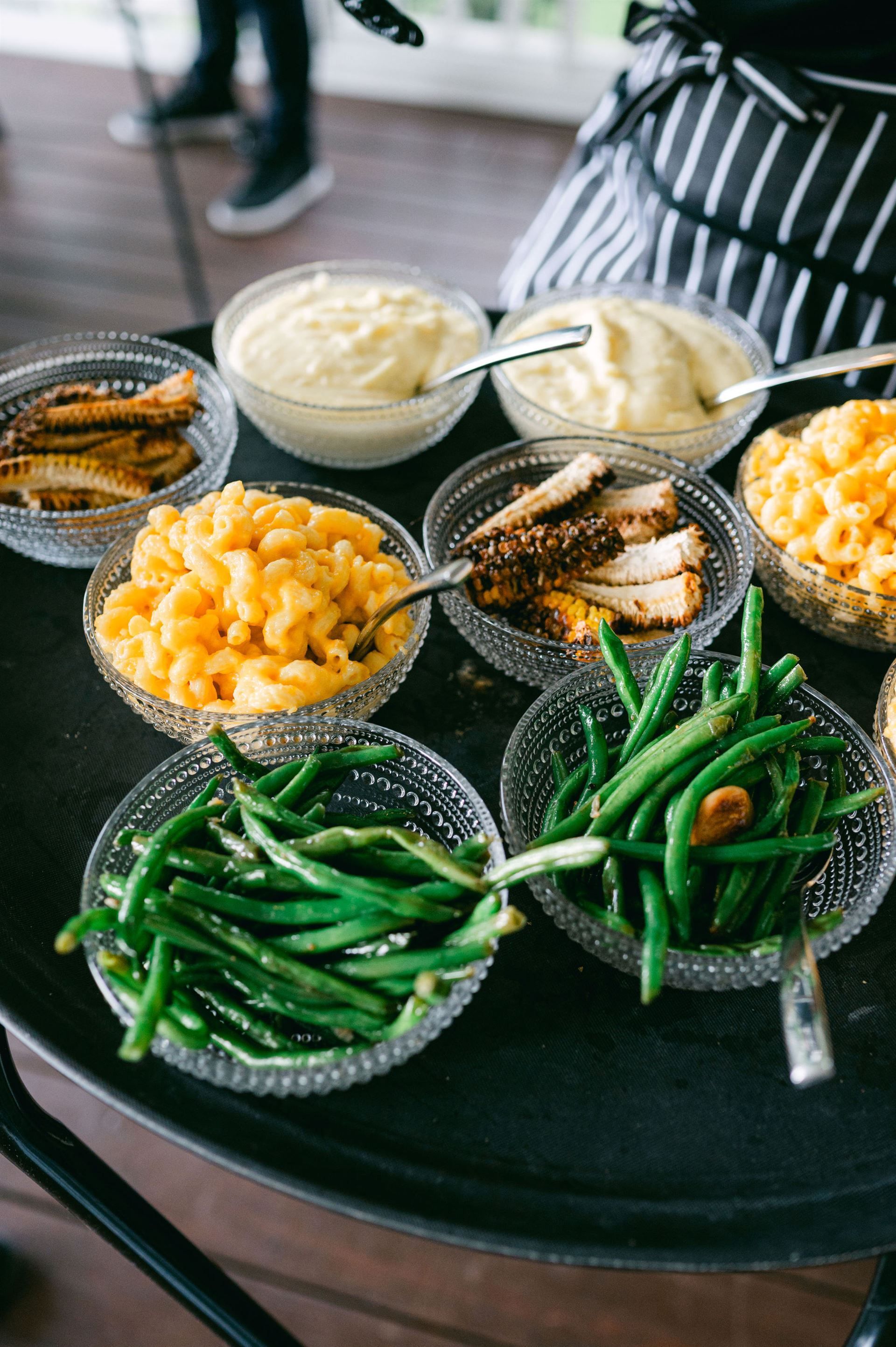 Tray of side dishes: mashed potatoes, mac and cheese, green beans, and roasted meat.