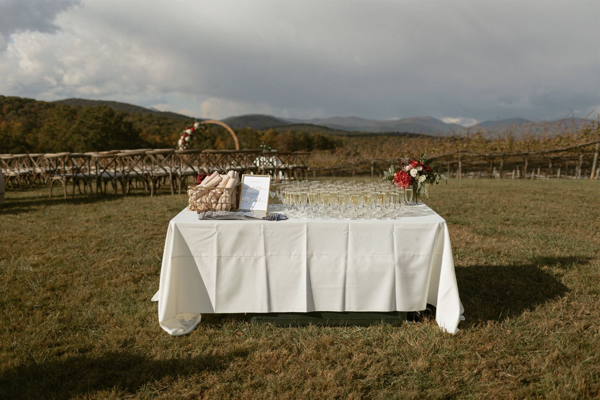 Table set with champagne flutes outdoors, with mountain and chairs in the background.