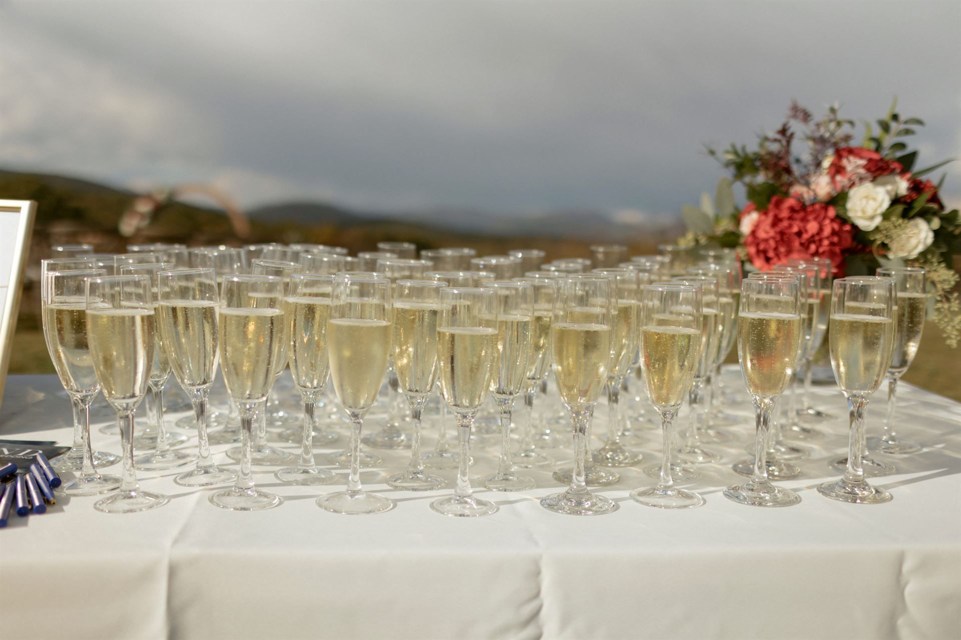 Table with champagne flutes, flowers, and a scenic outdoor background.