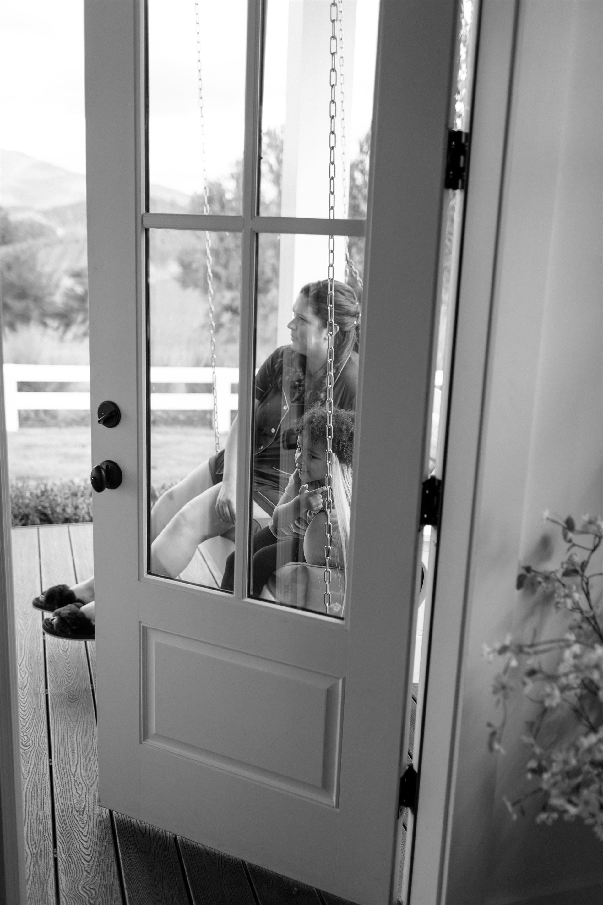 Open white door reveals a person sitting outside with a view of greenery.