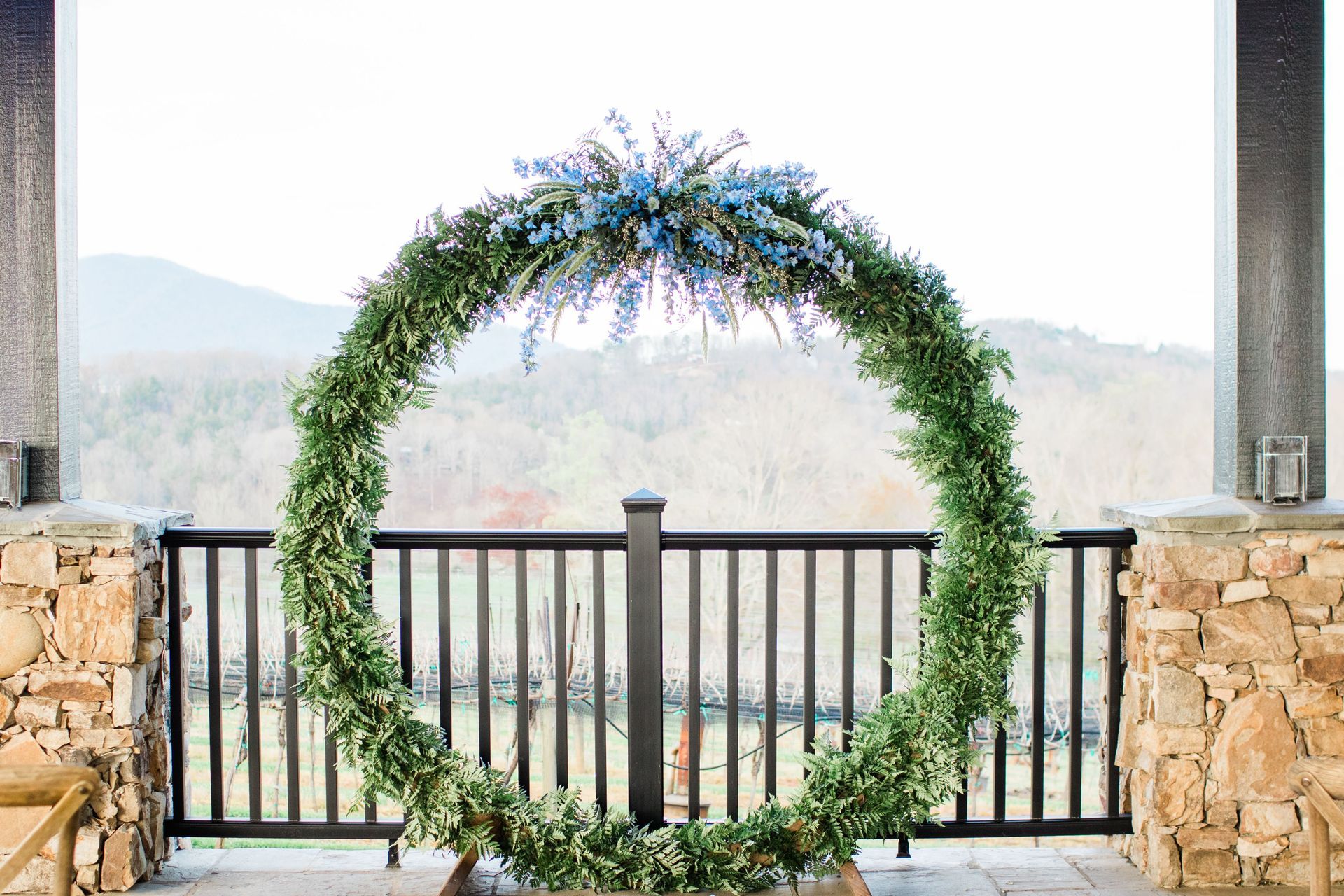 Circular floral wedding arch with blue and green flowers, outdoors.