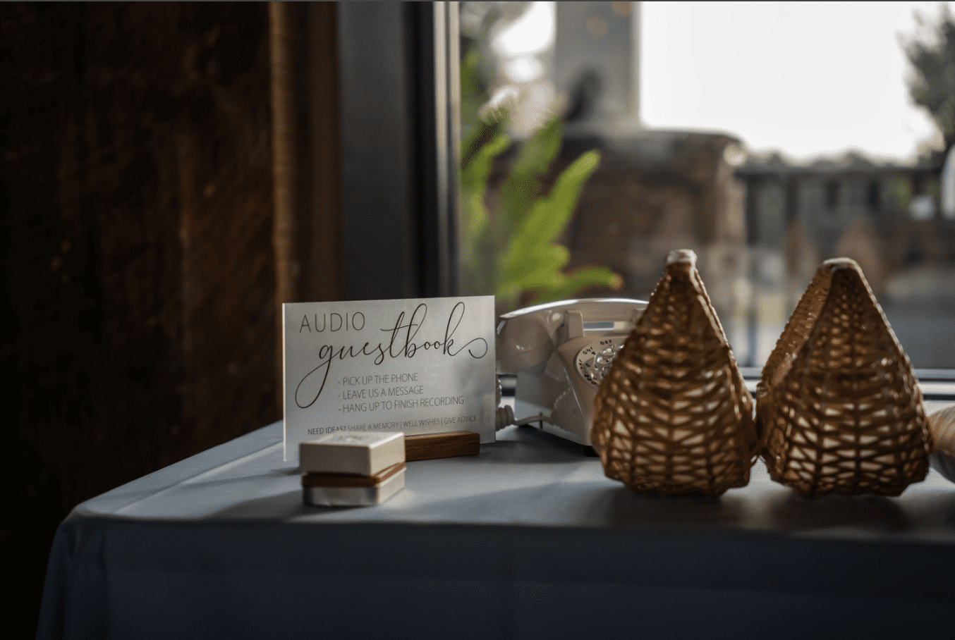 Wedding guest book table with sign, baskets, and small gift box.