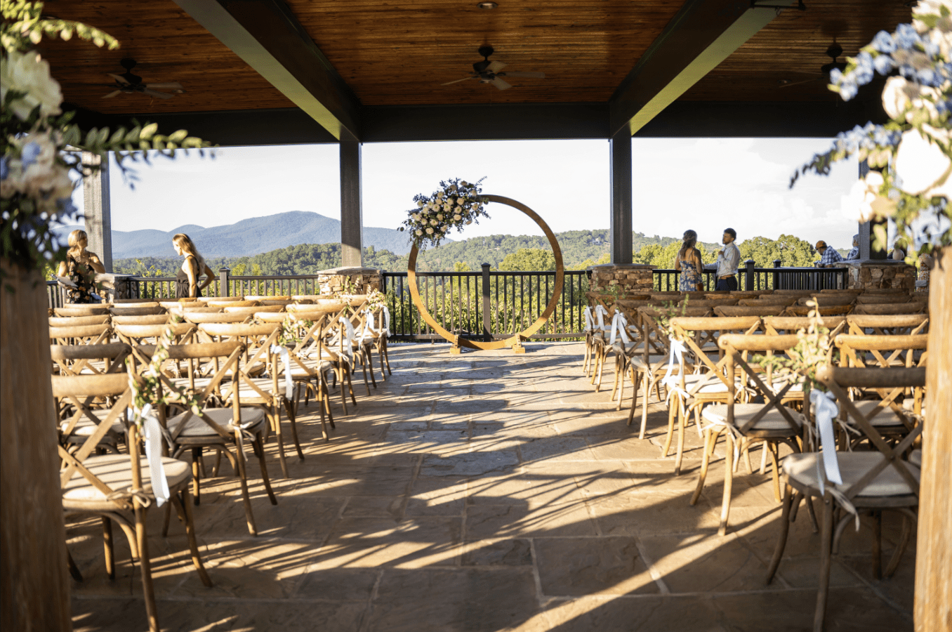 Wedding ceremony setup outdoors with mountain backdrop and circular floral arch.