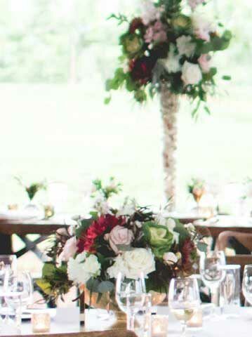 A table with a vase of flowers and wine glasses on it.