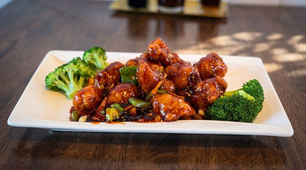 Plated glazed chicken with broccoli florets on a white rectangular dish