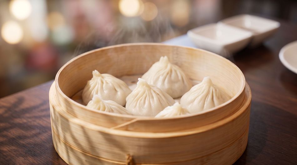 Steamed dumplings in a bamboo basket on a wooden table