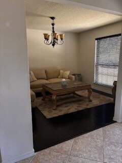 Living room with beige sectional, wooden coffee table, chandelier, and window blinds on tiled floor