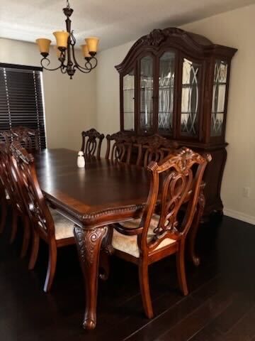 Formal dining room with dark wood table, carved chairs, china cabinet, and chandelier