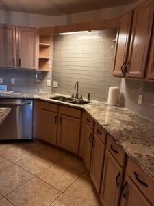 Modern kitchen with wood cabinets, granite countertops, tiled backsplash, stainless dishwasher
