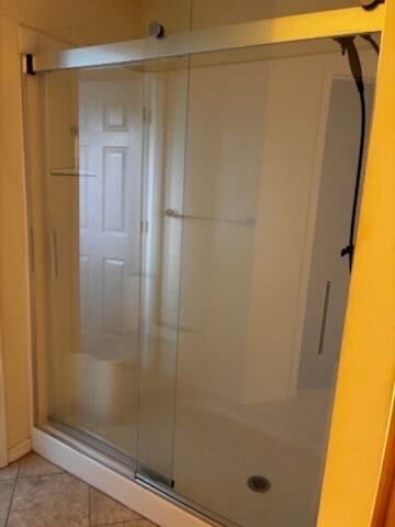 Glass shower door with silver frame and frosted panels in a beige bathroom