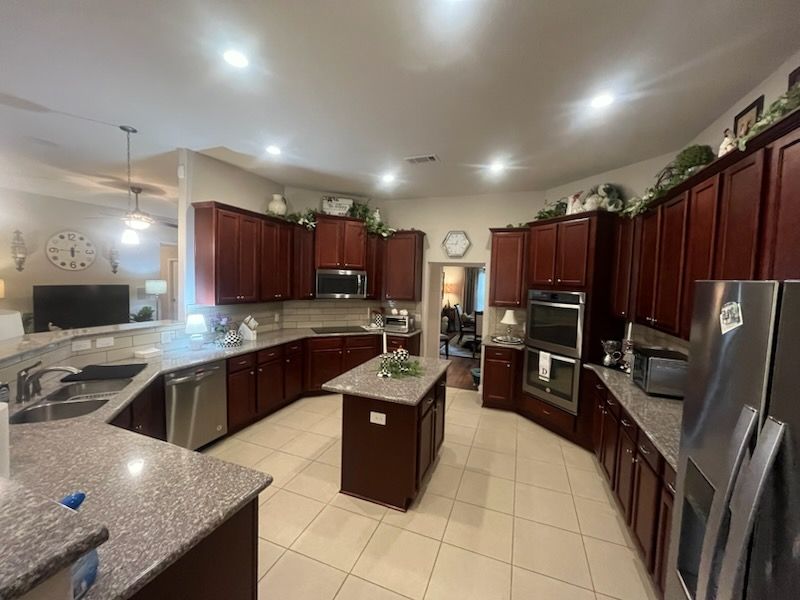 Spacious kitchen with dark wood cabinets, stainless steel appliances, granite countertops, and an island.