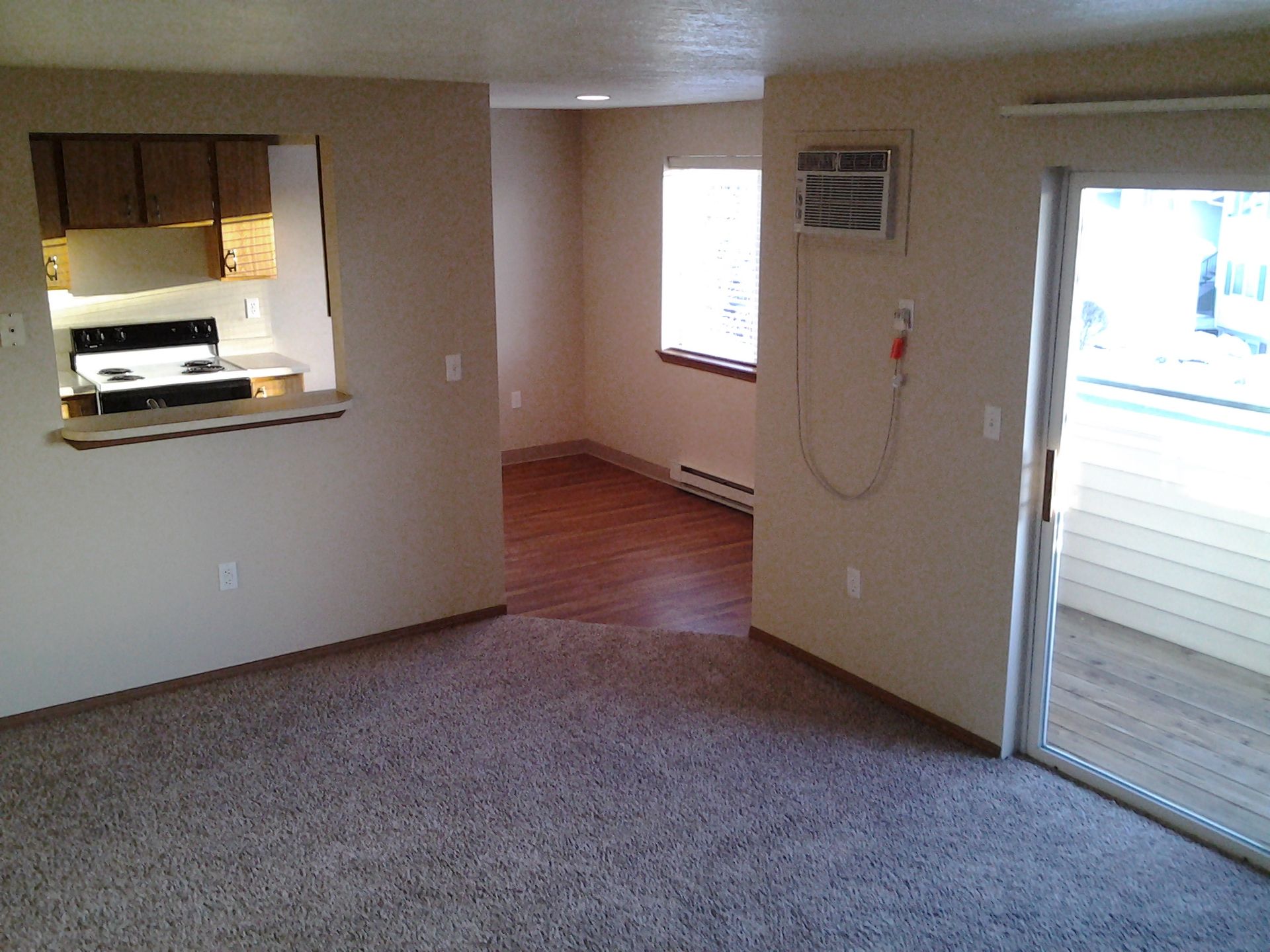 A living room with a sliding glass door leading to a kitchen