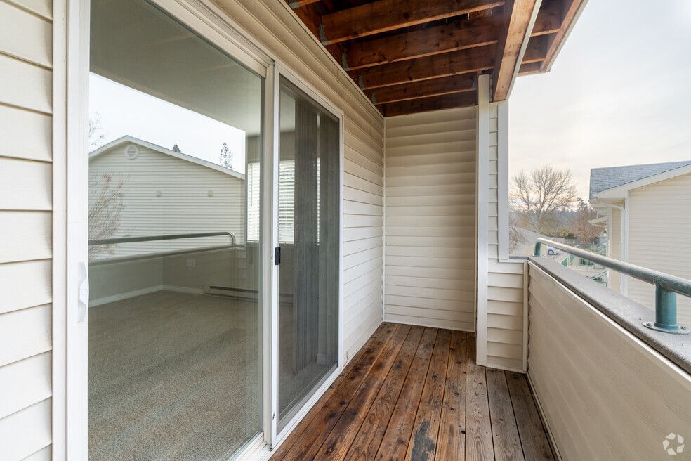 An empty balcony with a sliding glass door and a wooden deck.