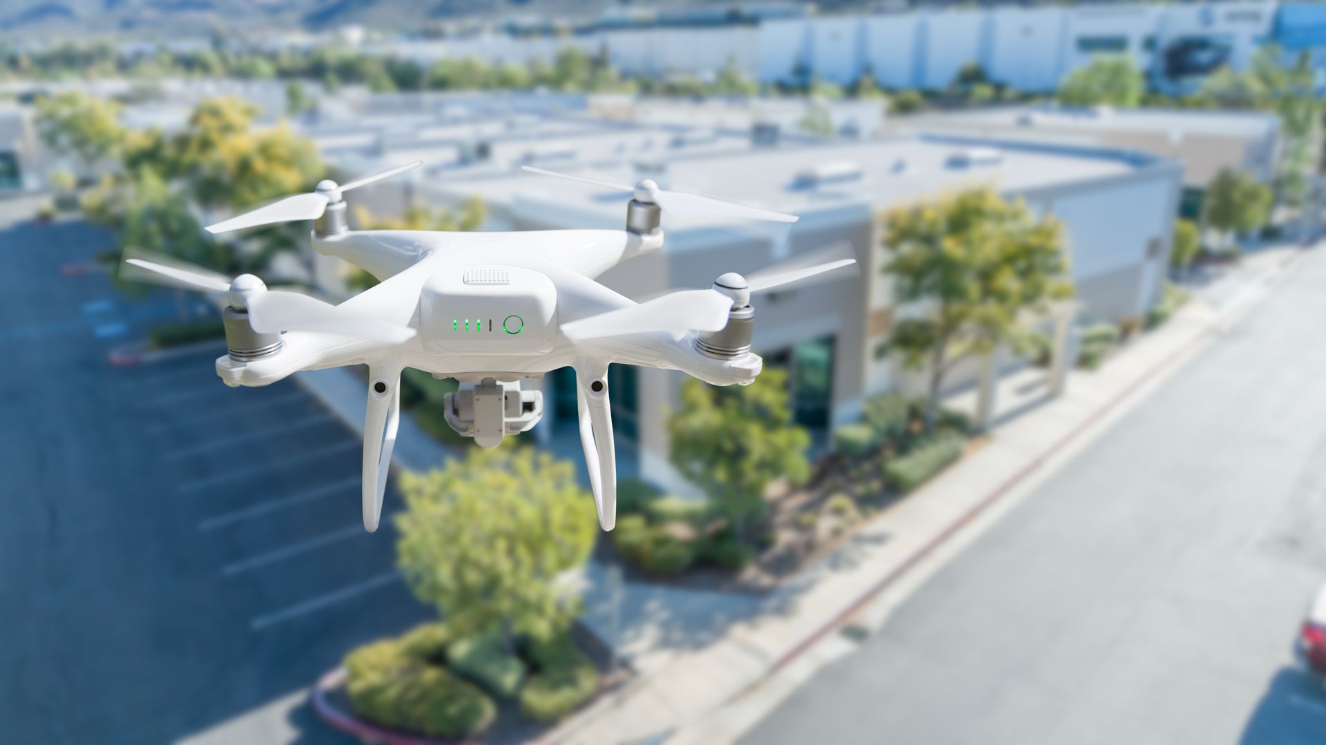 A White Drone Hovers in Mid-Air Above a Paved Parking Lot — Environment Restoration Solutions in Tweed Heads, NSW