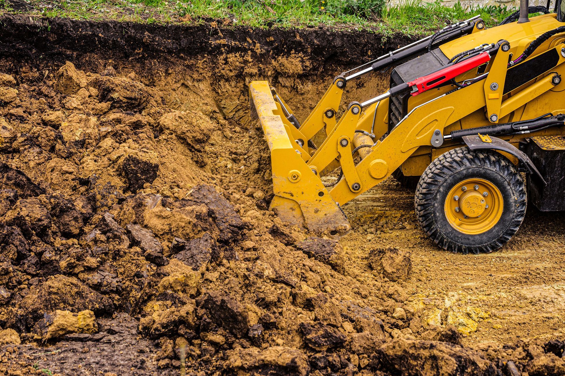 A Yellow Tractor-loader Pushes a Large Pile of Earth  — Environment Restoration Solutions in Coffs Harbour, NSW