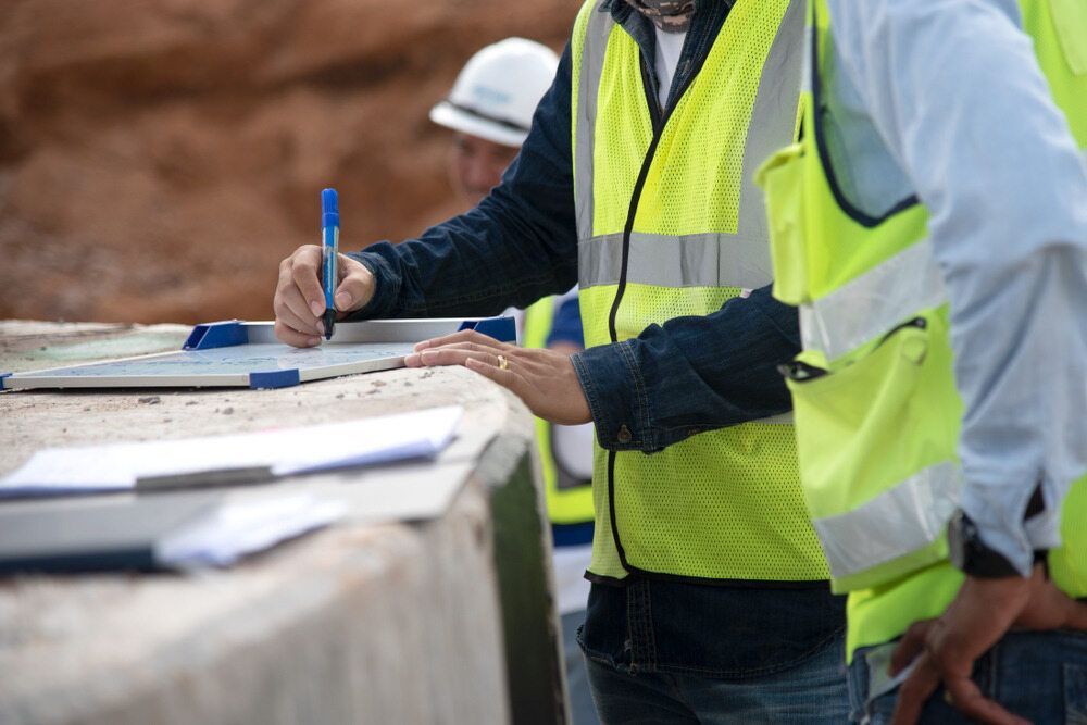 Construction Workers in High-visibility Vests Reviewing Blueprints — Environment Restoration Solutions in Coffs Harbour, NSW