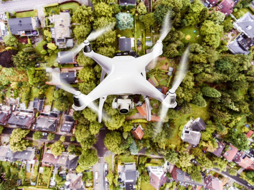 A White Quadcopter Drone Hovers Above a Residential Neighborhood — Environment Restoration Solutions in Armidale, NSW