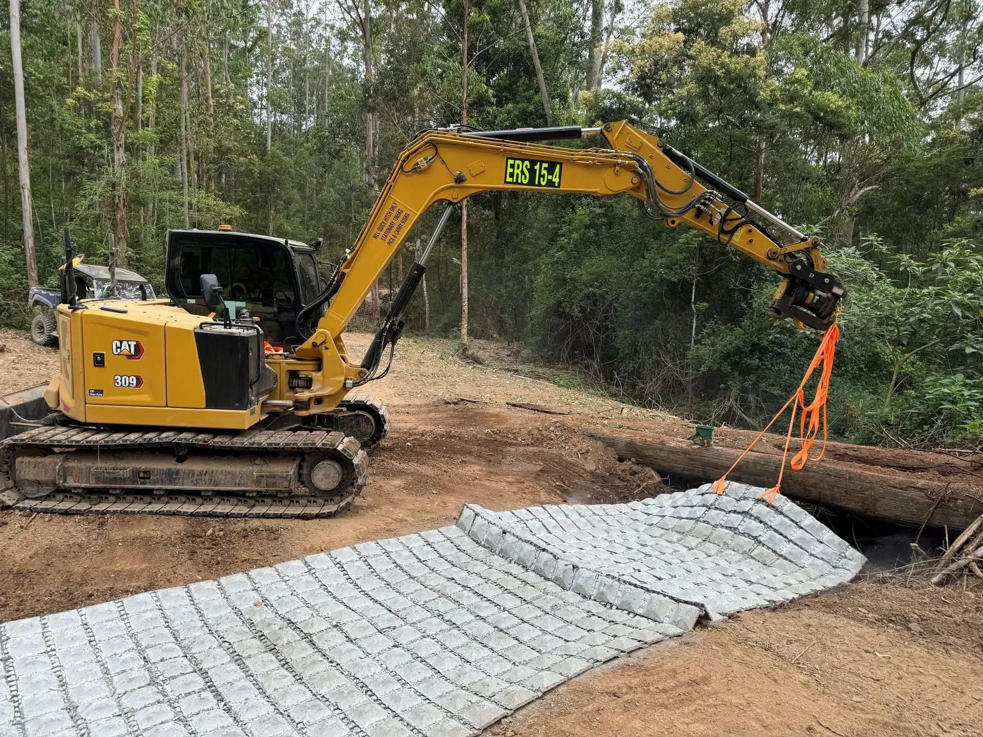 A Yellow Excavator Uses Orange Straps to Lift a Large Log — Environment Restoration Solutions in Waterview Heights, NSW