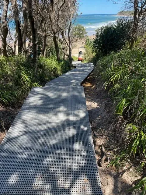 A Metal Grate Boardwalk Slopes Downhill Through Coastal Path — Environment Restoration Solutions in Waterview Heights, NSW