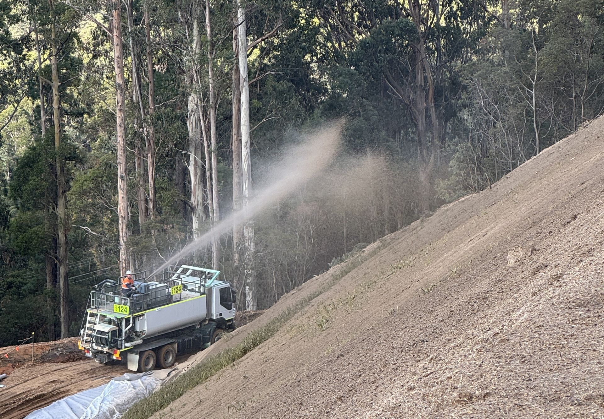 Water Truck Spraying a Steep Dirt Slope in A Forest Clearing — Environment Restoration Solutions in Waterview Heights, NSW