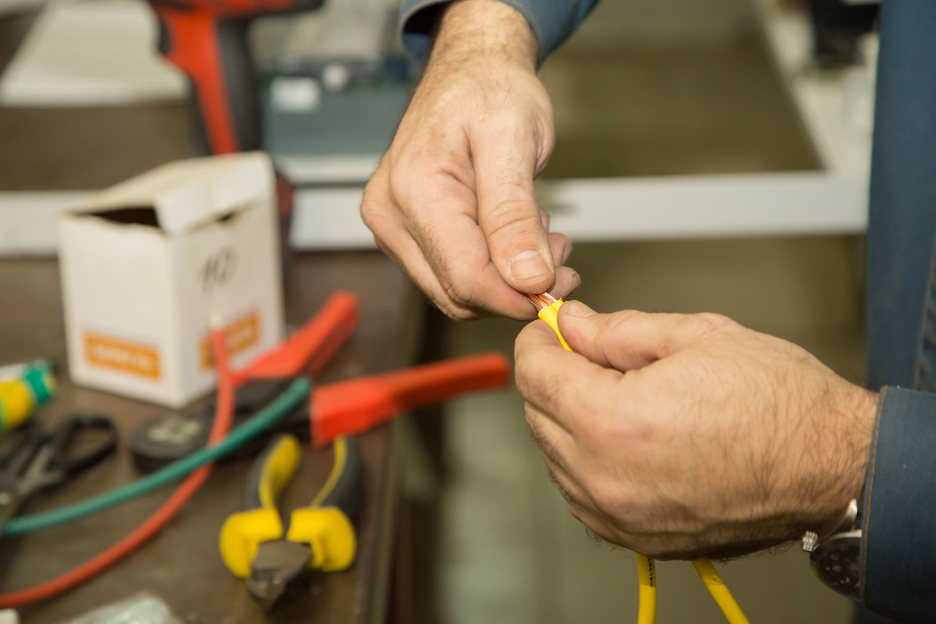 Person's hands stripping wire.
