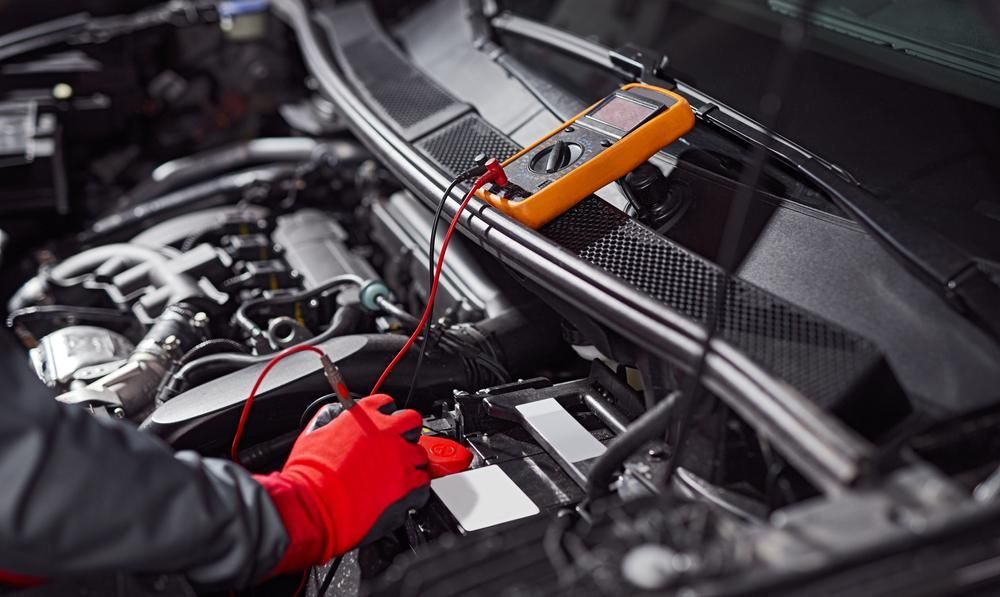 A Mechanic Is Working on A Car Engine with A Multimeter — Belmont Auto Electrics and Air Conditioning in Belmont, NSW