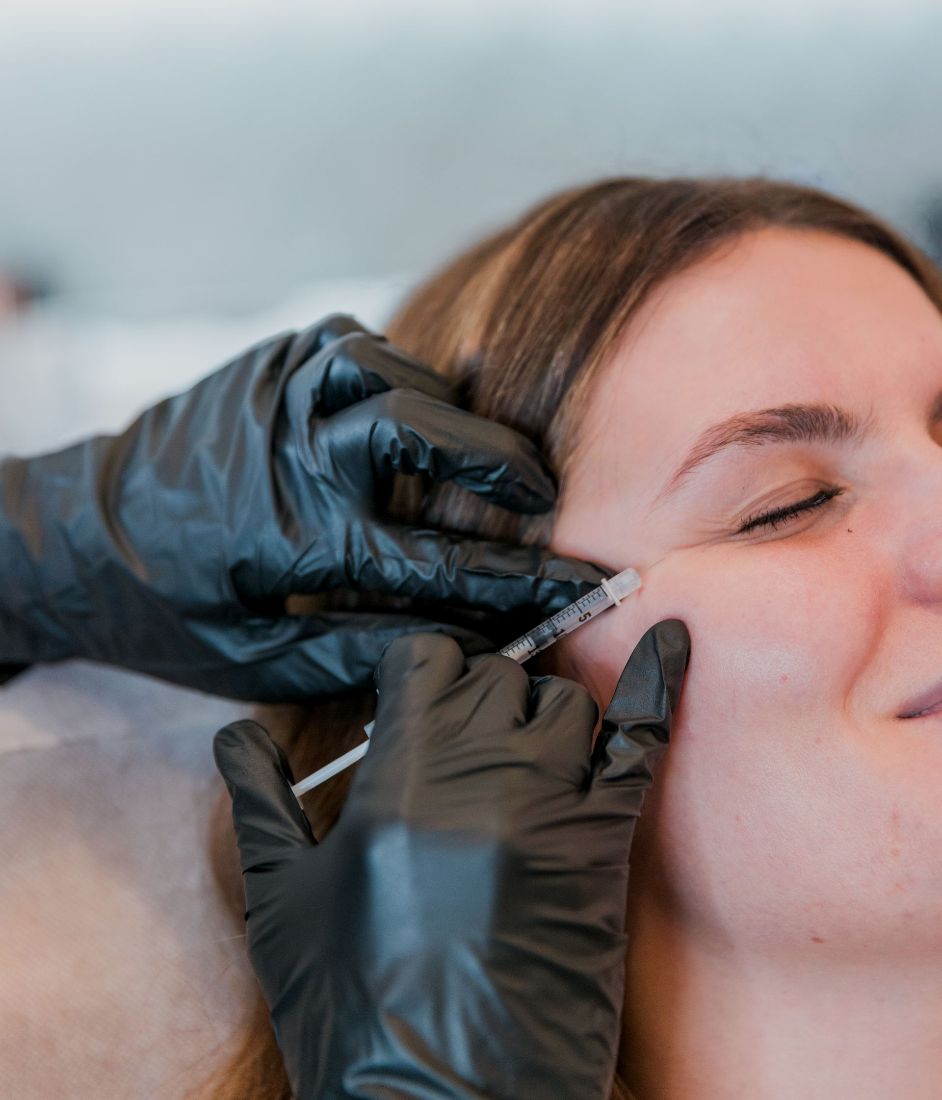 A man is getting a botox injection in his forehead.