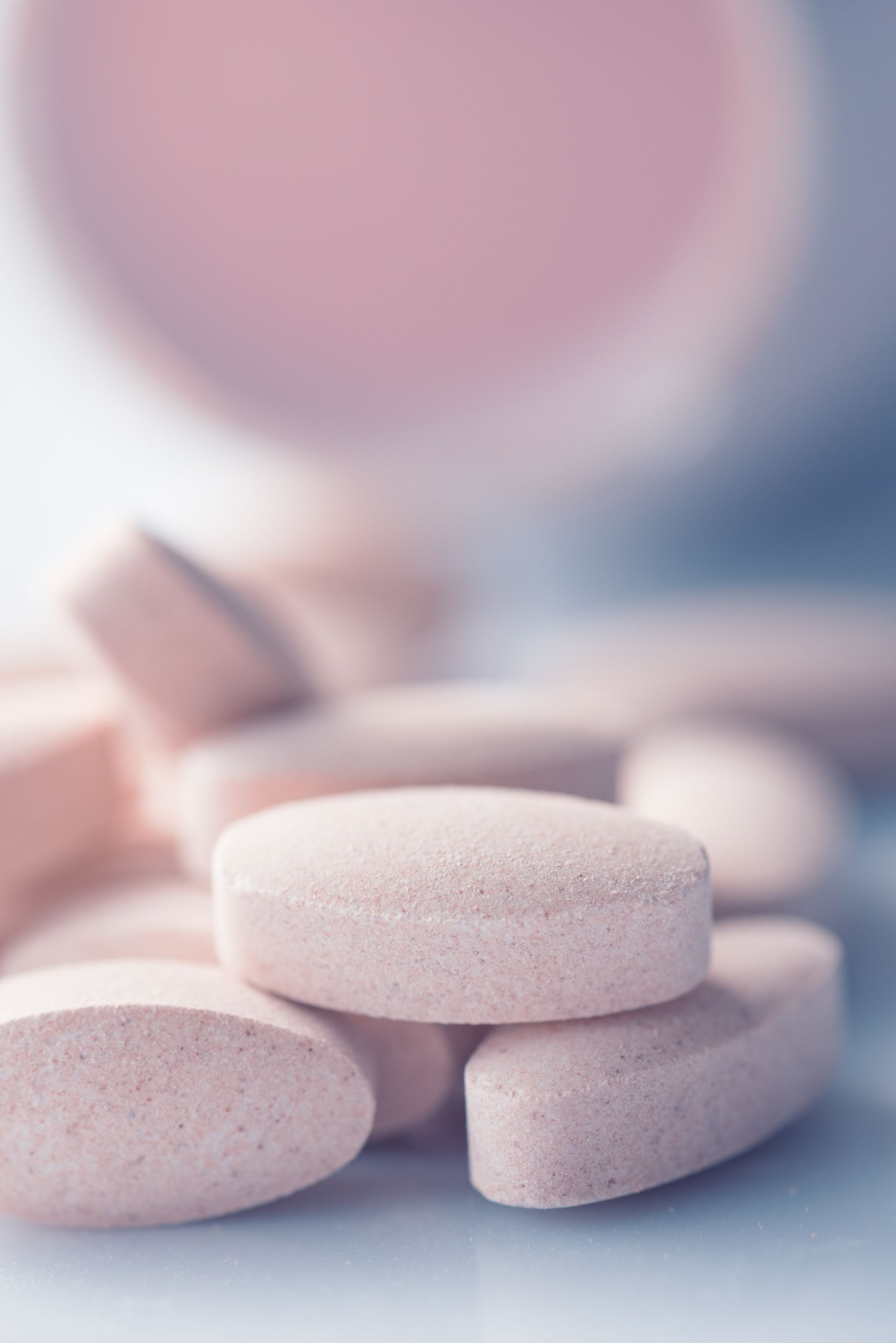 A close up of a pile of pink pills on a table.
