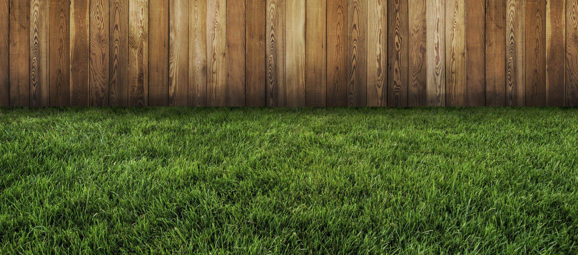 Wood privacy fence installed along a lush green lawn.