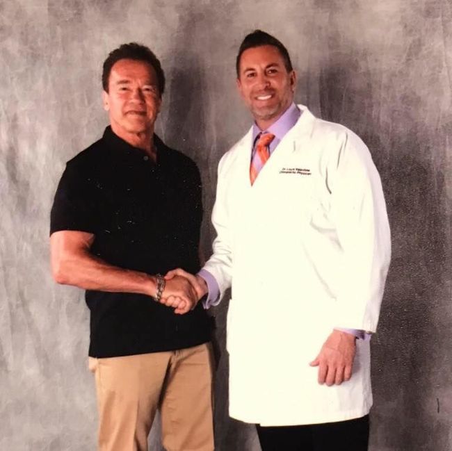 Dr. Louis Valentine shaking hands with Arnold Schwarzenegger