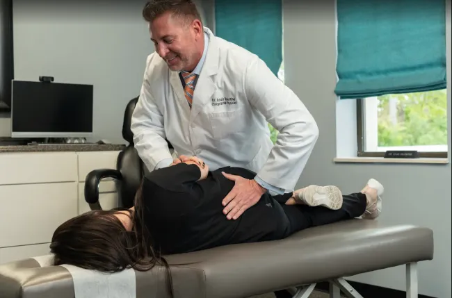 Chiropractor adjusting a patient lying face down on a treatment table in a clinic