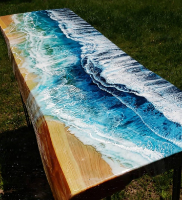 A wooden table with a painting of the ocean on it.