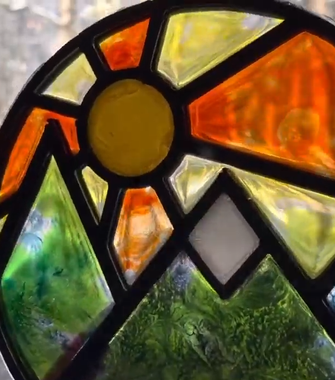 A close up of a stained glass window with a sun in the middle